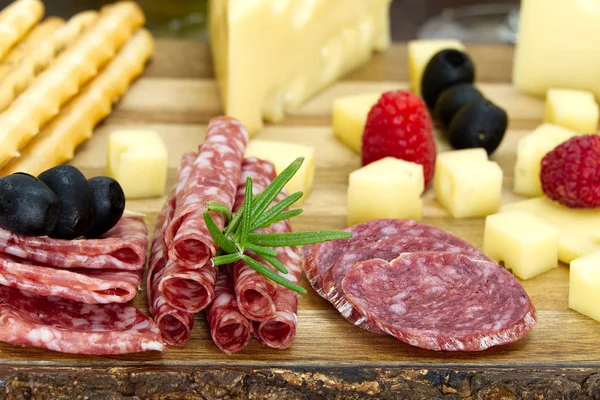 Snack antipasti de carne y queso con jamón Prosciutto, parmesano, queso azul, melón melón y aceitunas sobre tabla de servir de madera de olivo sobre fondo oscuro — Foto de Stock