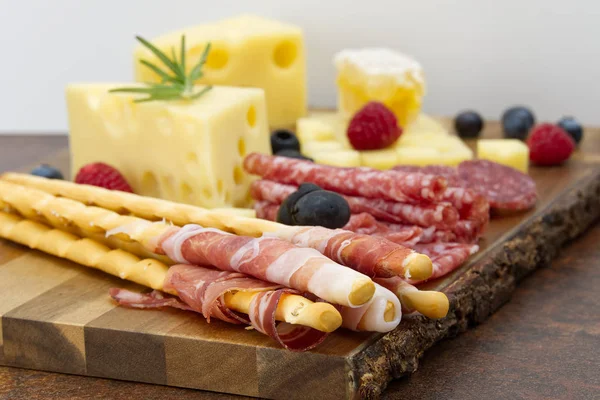 Carne e queijo prato antipasti lanche com presunto Prosciutto, parmesão, queijo azul, melão cantalupo e azeitonas em madeira de oliveira que serve bordo no fundo escuro — Fotografia de Stock