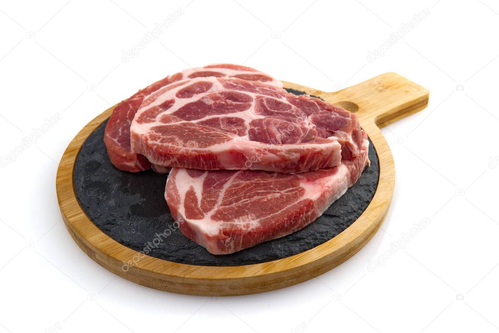two raw pork slices on black stone plate, isolated on white.