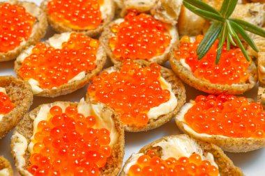 Beyaz tabakta kırmızı havyarlı sandviçler.