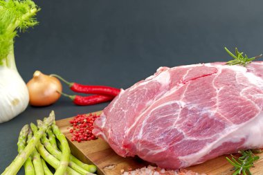 Taze çiğ domuz boynu, ahşap tahtada baharatlar ve sebzeler, siyah veya gri arka planda izole edilmiş..