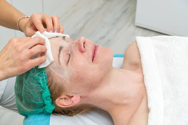 Schoonheidsspecialiste reinigt gezicht. Jonge vrouw in een schoonheidssalon. Cosmetologisch concept. De cosmetoloog voert een procedure uit om het gezicht te reinigen met een probleemhuid. Anti-leeftijd en rimpel. — Stockfoto