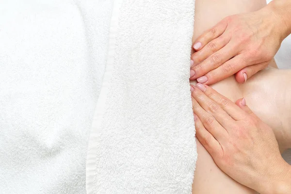 Massage av en ung kvinnlig kropp utan huvud, med händerna på en massör. Patientens kropp är täckt med en vit handduk. blank för reklam, flygblad, banner. — Stockfoto