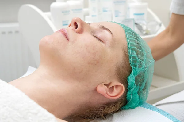 Schoonheidsspecialiste reinigt gezicht. Jonge vrouw in een schoonheidssalon. Cosmetologisch concept. De cosmetoloog voert een procedure uit om het gezicht te reinigen met een probleemhuid. Anti-leeftijd en rimpel. — Stockfoto