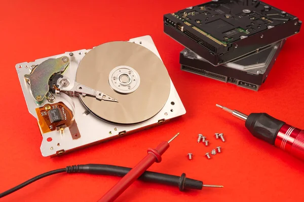 Hdd - hard disk drive. Hard disk repair concept. The hard drive is designed to store data of all mankind, so timely monitoring is very important. Pc industry. Disassembled hard disk on red Lush lava
