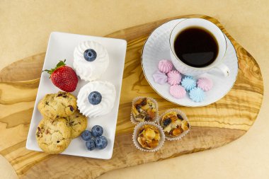 breakfast, coffee Oat cookies with Strawberry and bize cookies with blueberry on olive wood board