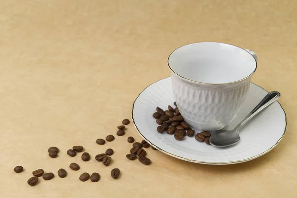 Taza de café blanco vacía con borde dorado y semillas de café sobre la mesa. de cerca — Foto de Stock