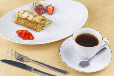 Zeytin ağacının üzerinde altın kenarlı kahve fincanı. Kahvaltı, yulaf ezmeli kurabiye, ahududu ve mini toska keki.