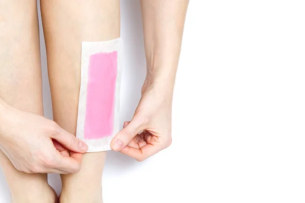 Vrouw met roze wasstrips. mooie vrouw doet ontharing voor haar benen met waxen, geïsoleerd op wit — Stockfoto