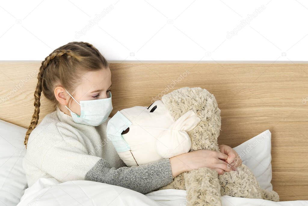A sick sad child in a mask with a temperature and a headache lies in bed. Flu colds disease virus bacterium. girl with toy in bed room wear protection mask, Protect Against Coronavirus concept.