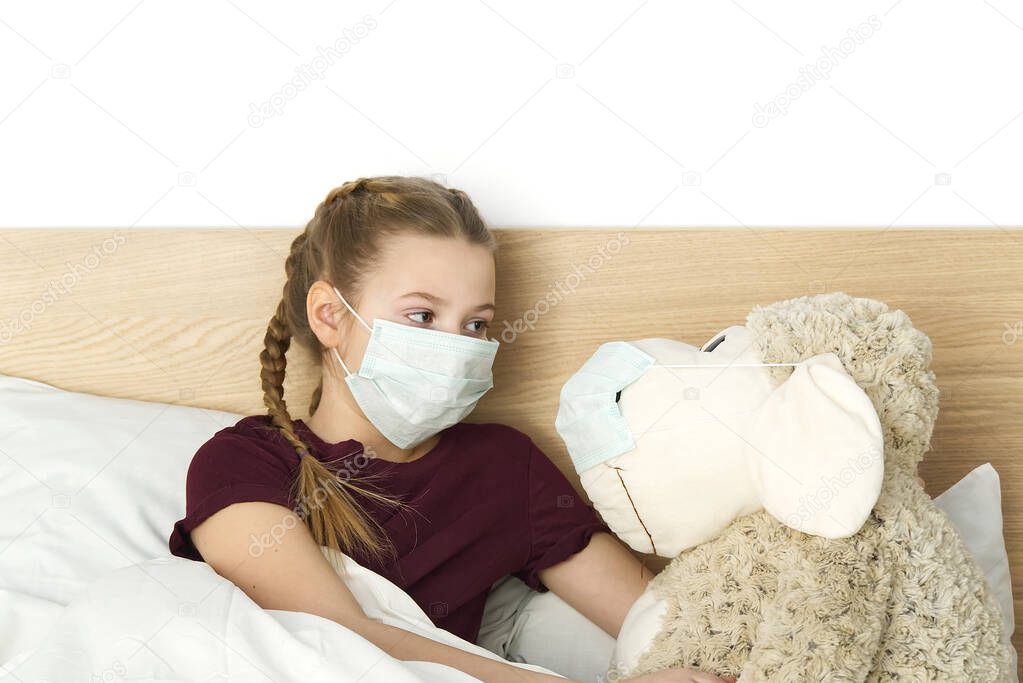 A sick sad child in a mask with a temperature and a headache lies in bed. Flu colds disease virus bacterium. girl with toy in bed room wear protection mask, Protect Against Coronavirus concept.