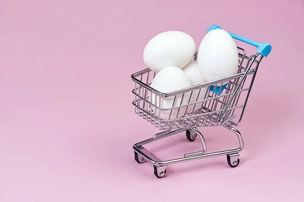 Hønsehvite egg i en handlevogn. isolert på rosa – stockfoto
