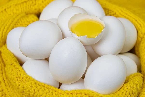 white chicken eggs in yellow wool sweater. lot of white eggs close up. broken chicken white egg.