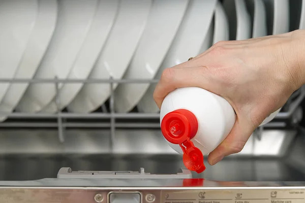 Aus nächster Nähe in die volle Spülmaschine. integrierte Spülmaschine voll beladen. Frau hält Spülmittel-Tablette in der Hand. — Stockfoto