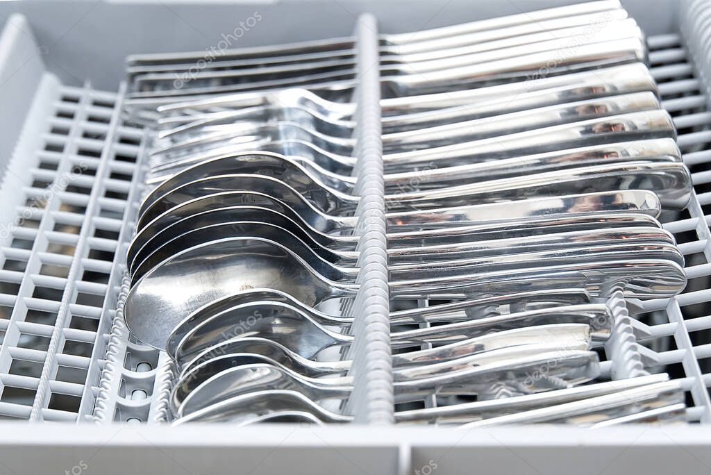Clean cutlery is in the dishwasher. close up