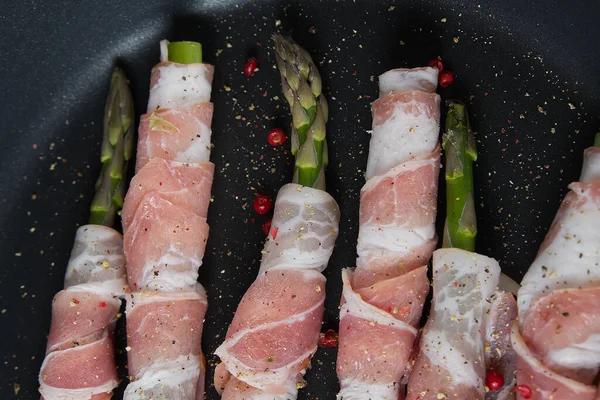 Bacon saboroso em torno de espargos na frigideira. Espargos frescos de perto - prontos para cozinhar. conceito de receitas alimentares saudáveis — Fotografia de Stock