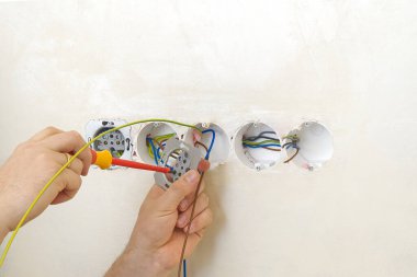 Elektrikçi bej duvarlara eu standartlarıyla prizler kuruyor