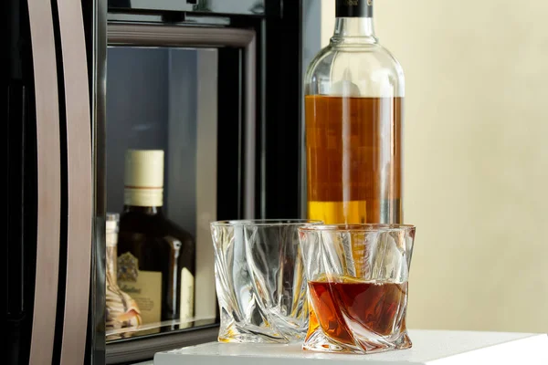 open hatch of a mini bar in a modern refrigerator. home mini bar in the fridge. a glass carafe full of whiskey, cognac or an alcoholic drink, ready to be poured into glasses