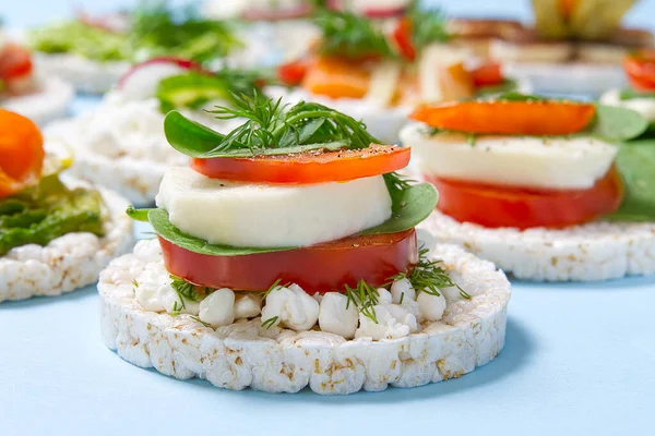 healthy food rice cake sandwich on light blue background. Rice cookies sandwich on table with sandwiches on background. Rice cakes with mozzarella, tomato, basil, dill, spices