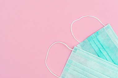 Antivirüs maskesi. İlaç maskesi. Plastik kulak bantlı cerrahi maske. Virüs, grip, soğuk algınlığı ve koronavirüsü önleme. kopyalama alanı olan pembe arkaplan üzerinde.