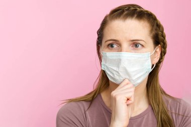 Tıbbi maske takan kadın. Maskeli kadın, grip virüsüne karşı koruma. Evde koruyucu maskeli bir kulak. Virüsü ve salgın hastalıkları durdurun. Coronavirüs 'ü durdurun. pembe arkaplanda.