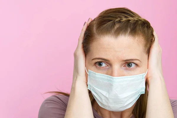 Женщина в медицинской маске, затыкающая уши руками, не хочет слушать о вирусе. Европейская молодая женщина игнорирует шум или новости о коронавирусе. Концепция без новостей — стоковое фото