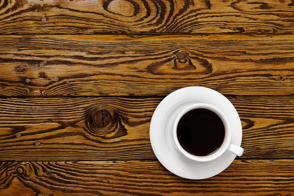 Cangkir kopi putih pemandangan atas di meja kayu tua. Aromatic coffee drink in white cup on brown wood table — Stok Foto