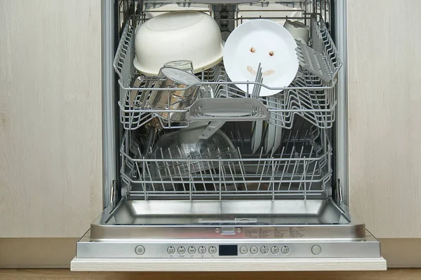 Fine washed dishes in the dishwasher. Integrated Dishwasher with white plates front vew and happy emotion on plate. Easy home cleaning concept.