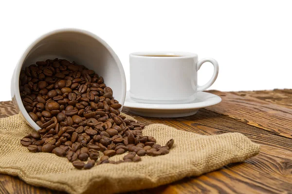 Taza de café blanco con bebida aromática de café en la mesa de madera marrón. Semillas de café en mesa de madera antigua con taza de bebida de café con fondo blanco para espacio de copia . — Foto de Stock