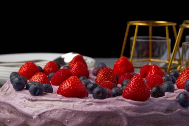 Ev yapımı çilekli cheesecake. Çilekli cheesecake, böğürtlen ve ahududu gri ahşap masa üzerinde mumlar ve tabaklar ile süslenmiş