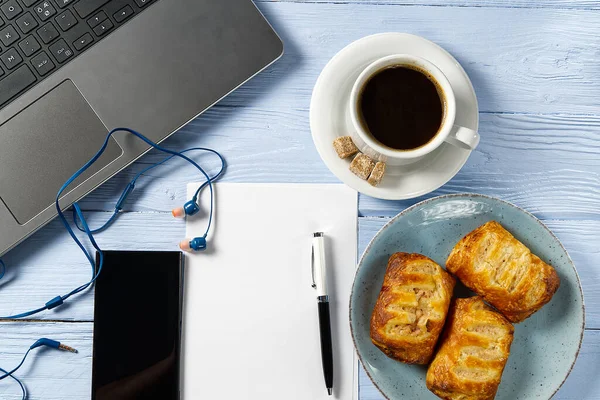 Laptop com xícara de café e padaria em luz azul velha mesa de madeira. Caderno com xícara de café fresco no escritório em casa. Trabalhando a partir de casa conceito — Fotografia de Stock