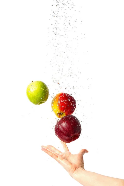 Mano atrapa tres manzanas voladoras bajo las gotas de agua. Tres variedades diferentes de manzana en vuelo sobre un fondo blanco. Manzana roja, verde y rojo-verde, pulverización de agua. lavar frutas y manzanas — Foto de Stock