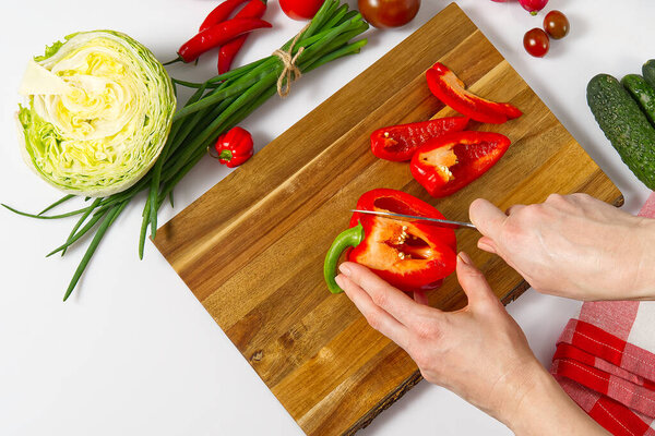 salad from fresh vegetables in a plate on a table. bowl of salad with vegetables and greens on white table. Women preparing vegetable salad- close up shot. Domestic kitchen. Vegetarian food.