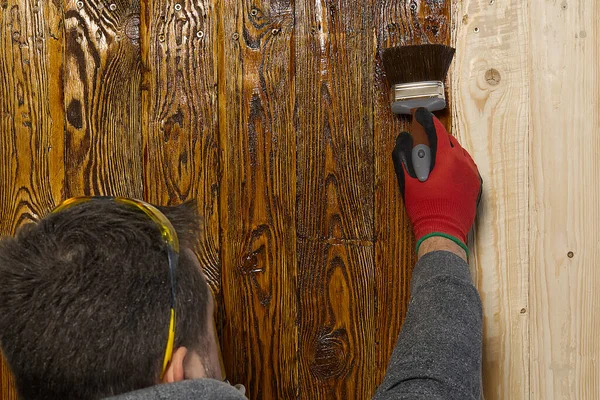 Ενηλίκων ξυλουργός τεχνίτης ζωγραφική με νερό με βάση το χρώμα του ξύλου. Δουλειά για το σπίτι, κάντο μόνος σου. Βουρτσισμένη υφή ξύλου εμποτισμού με φυσικό έλαιο — Φωτογραφία Αρχείου