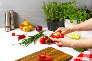 Masadaki tabakta taze sebzelerden yapılmış salata. Sebzeli ve sebzeli bir kase salata. Sebze salatası hazırlayan kadınlar. Yakın çekim. Ev mutfağı. Vejetaryen yemeği..