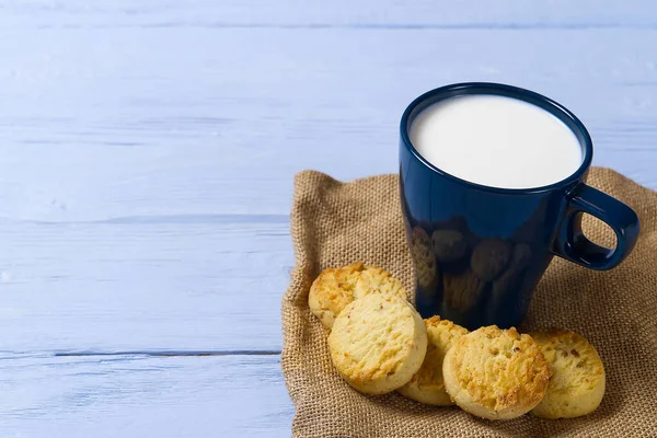 Becher mit warmer Milch und Keksen vor dem Schlafengehen. Blaue Tasse mit frischer Milch und leckeren Keksen. — Stockfoto