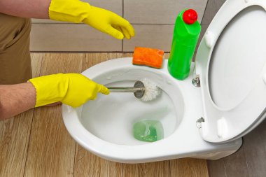 Sarı eldivenli adamlar klozeti temizliyor. ev temizliği kavramı.