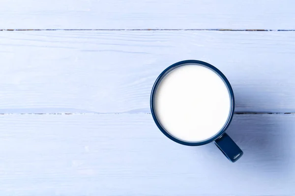 Tazza blu di latte su sfondo di legno azzurro. vista dall'alto - posa piatta. Tazza blu con latte . — Foto Stock