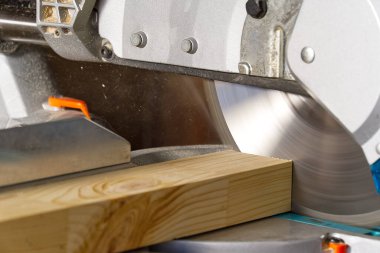 Ahşap atölyesinde elektrikli testere ile çalışan profesyonel dolap üreticilerine yakın çekim. Becerikli marangoz dairesel testereyle tahta kesiyor. Ahşap malzeme üretimi. Kereste fabrikası