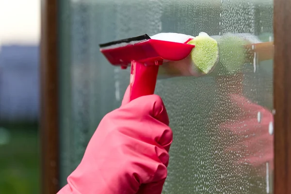 window cleaning. A woman in pink rubber gloves washes a window in a house. Happy Woman In Gloves Cleaning Window. Concept for home cleaning services