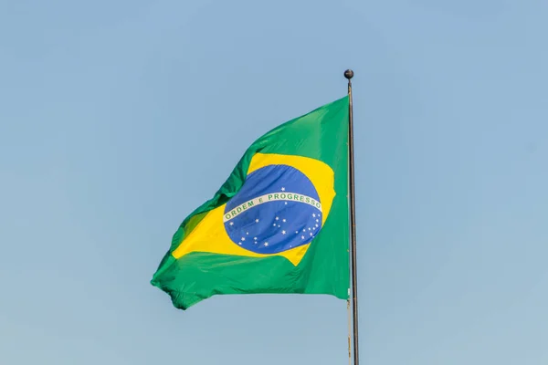 Бразильський прапор, що літає з синім небом — стокове фото