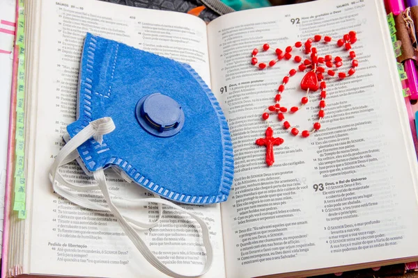 bible with blue mask and red rosary a lot of faith and protection against the corona virus in Brazil