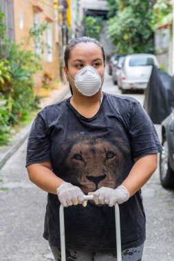 Eldivenli ve maskeli bir kadın alışveriş arabası tutuyor, Rio de Janeiro 'da koronavirüse karşı korunuyor.