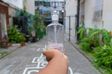 Rio de Janeiro 'da Coronavirus' a karşı korunmak için elinde bir şişe alkol jeli tutan esmer bir adam..