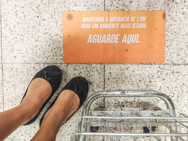 Damskie Stopy Obok Wózka Sklepowego Znakiem Podłodze Napisanym Języku Portugalskim — Zdjęcie stockowe