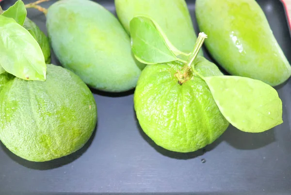 Grüne Mangofrüchte Orangen Auf Einem Zweig Mit Blättern Einem Teller — Stockfoto
