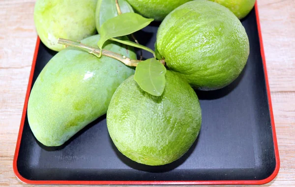 Grüne Mangofrüchte Orangen Auf Einem Zweig Mit Blättern Einem Teller — Stockfoto