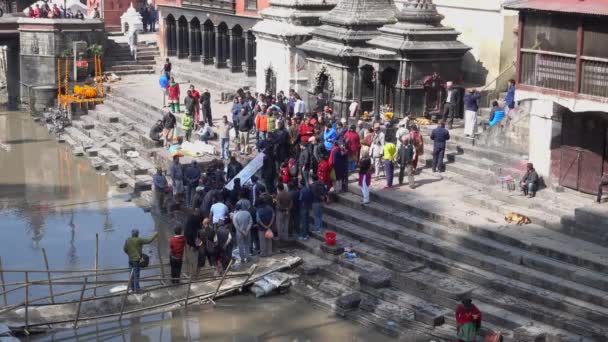 Kathmandu, Nepal, 25 maart 2017: De crematie ceremonie bij Pashupatinath tempel in Kathmandu en toegestane toerist en bezoeker te vangen de ceremonie langs de rivier van de Heilige Bagmati in Bhasmeshvar Ghat — Stockvideo