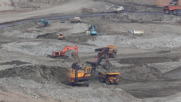 Heavy construction tipper trucks dump coal to the conveyor at coal mine — Stock Video