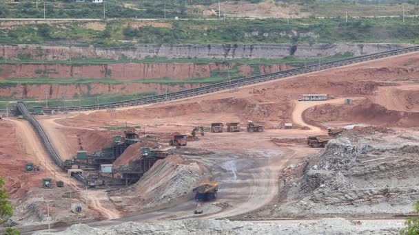 Heavy construction tipper trucks dump coal to the conveyor at coal mine — Stock Video